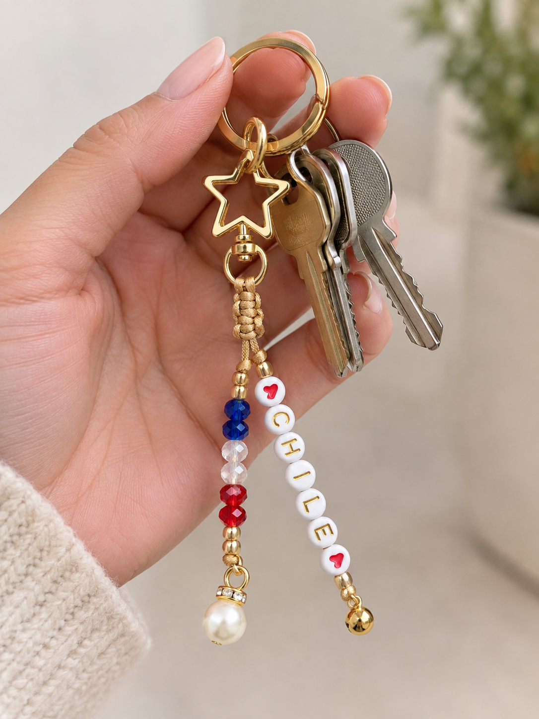 Llavero dorado con mosquetón en forma de estrella, cuentas con la palabra Chile entre corazones, cristales en azul, blanco y rojo.