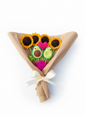 Ramo artesanal de flores tejidas que incluye 4 girasoles, un corazón rosado y una pareja de paltas amigurumi envuelto en papel café con un lazo blanco.