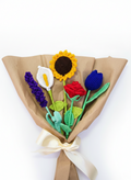 Ramo artesanal envuelto en papel café que incluye una cala, lavanda, una rosa, un girasol y un tulipán, todos tejidos a mano.